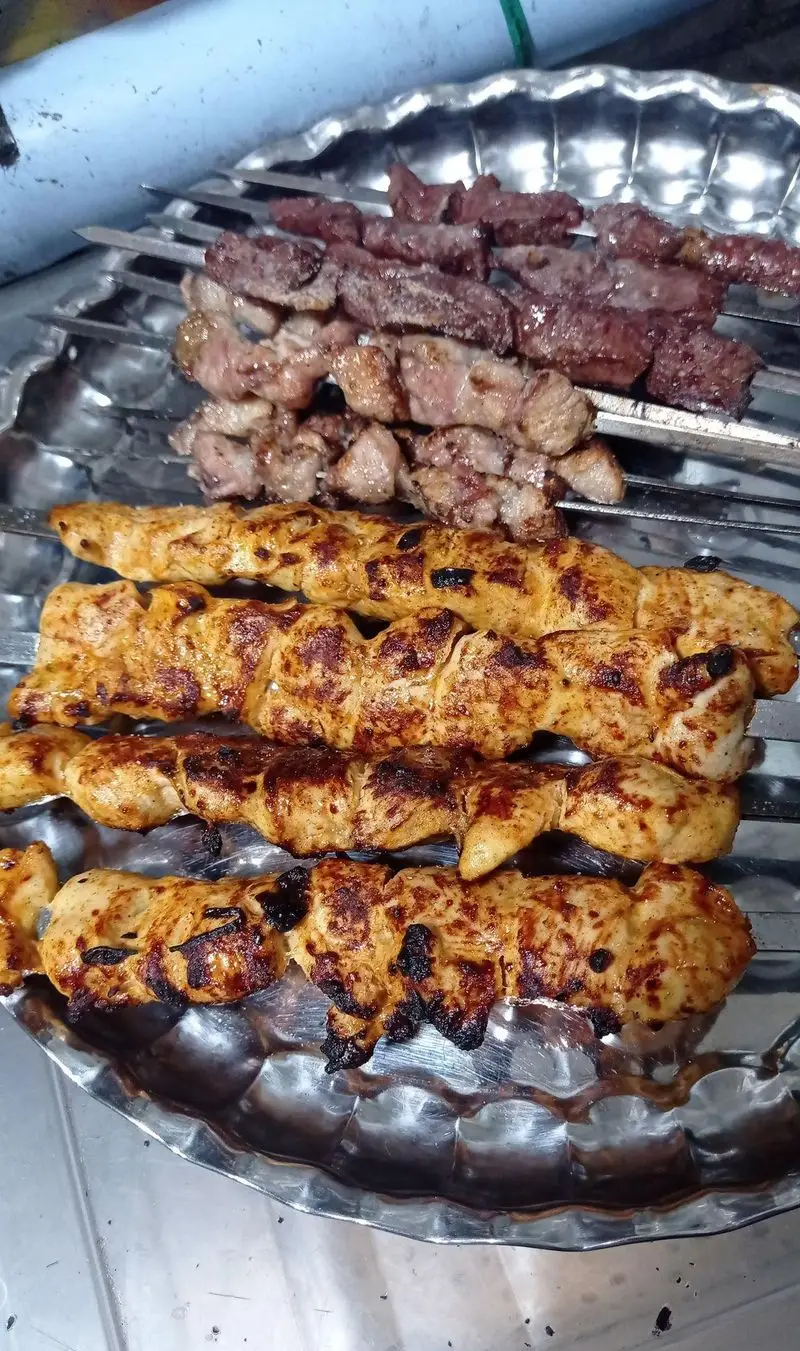 تصویری از کباب‌های خوش‌رنگ و تازه پخته شده جگر، دل، گوشت و مرغ روی سیخ در جگرکی لوکس طلائی آماده سرو.