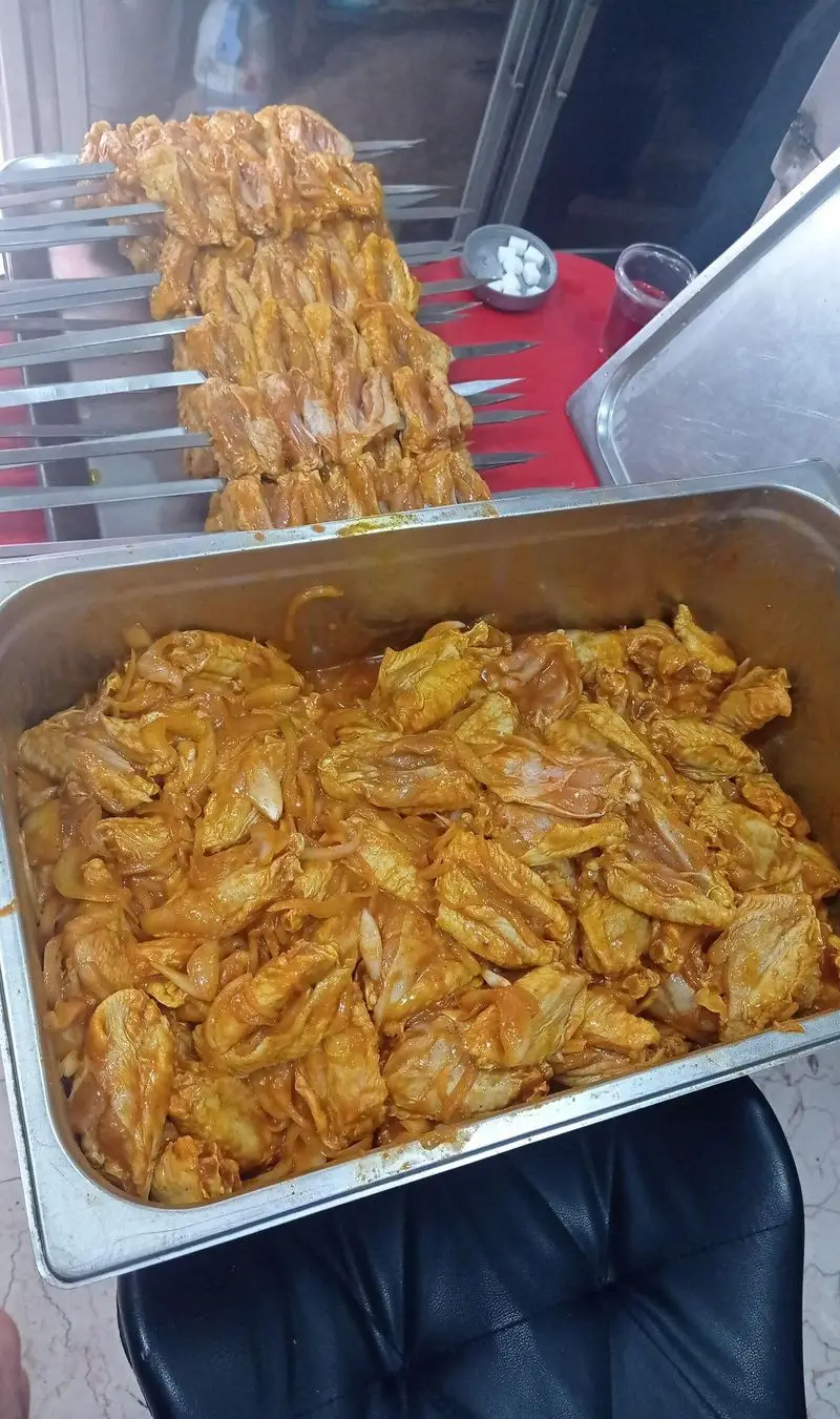 بال‌های جوجه کبابی تازه و مزه‌دار شده روی سیخ و در سینی، آماده طبخ در جگرکی لوکس طلائی با بهترین کیفیت و طعم.