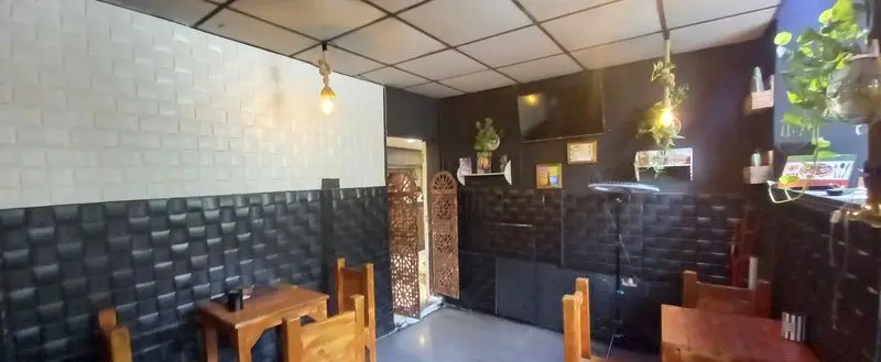 فضای داخلی دنج و مدرن رستوران هتل آپادانا با دیوارهای سفید و مشکی، نورپردازی گرم، میز و صندلی چوبی، و دکوراسیون گیاهی شیک.