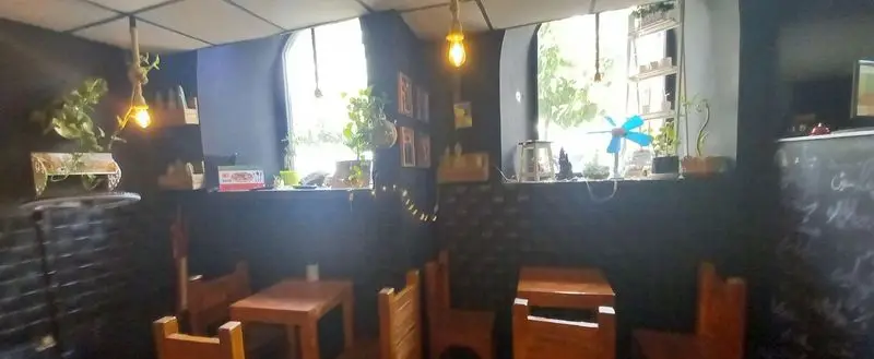 فضای داخلی رستوران هتل آپادانا: دکوراسیون مدرن با دیوارهای تیره، میز و صندلی چوبی، پنجره‌های بزرگ با منظره سرسبز و نورپردازی گرم و دلنشین.