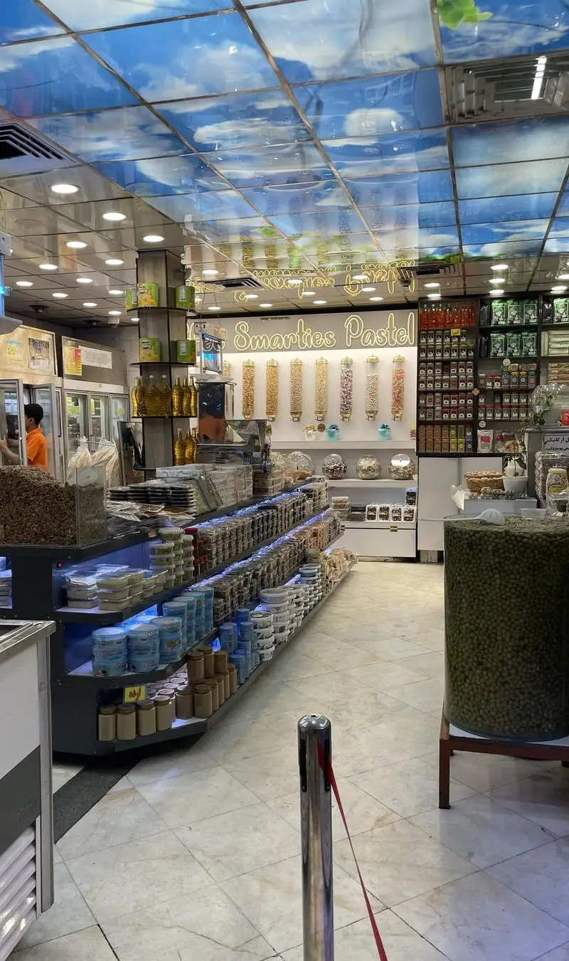 نمای داخلی فروشگاه بزرگ لبنیات سنتی و آبمیوه بستنی طرشت با سقفی طرح آسمان و قفسه‌های پر از آجیل، خشکبار و شیرینیجات.