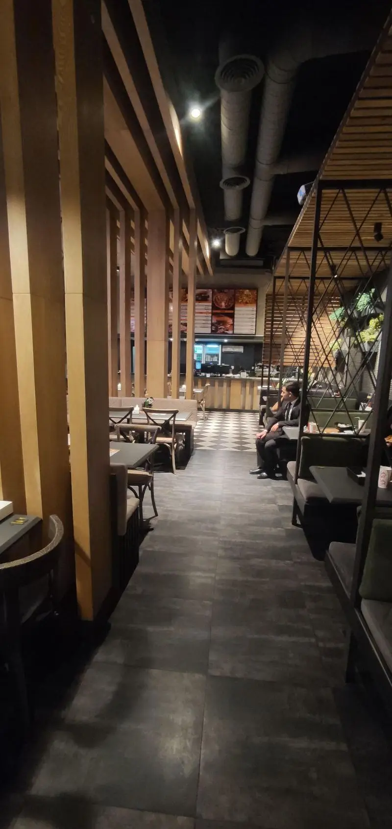 فضای داخلی مدرن و شیک رستوران ای تی اف شعبه کاشانی با دکوراسیون چوبی، سقف صنعتی و میز و صندلی‌های راحت برای مشتریان.