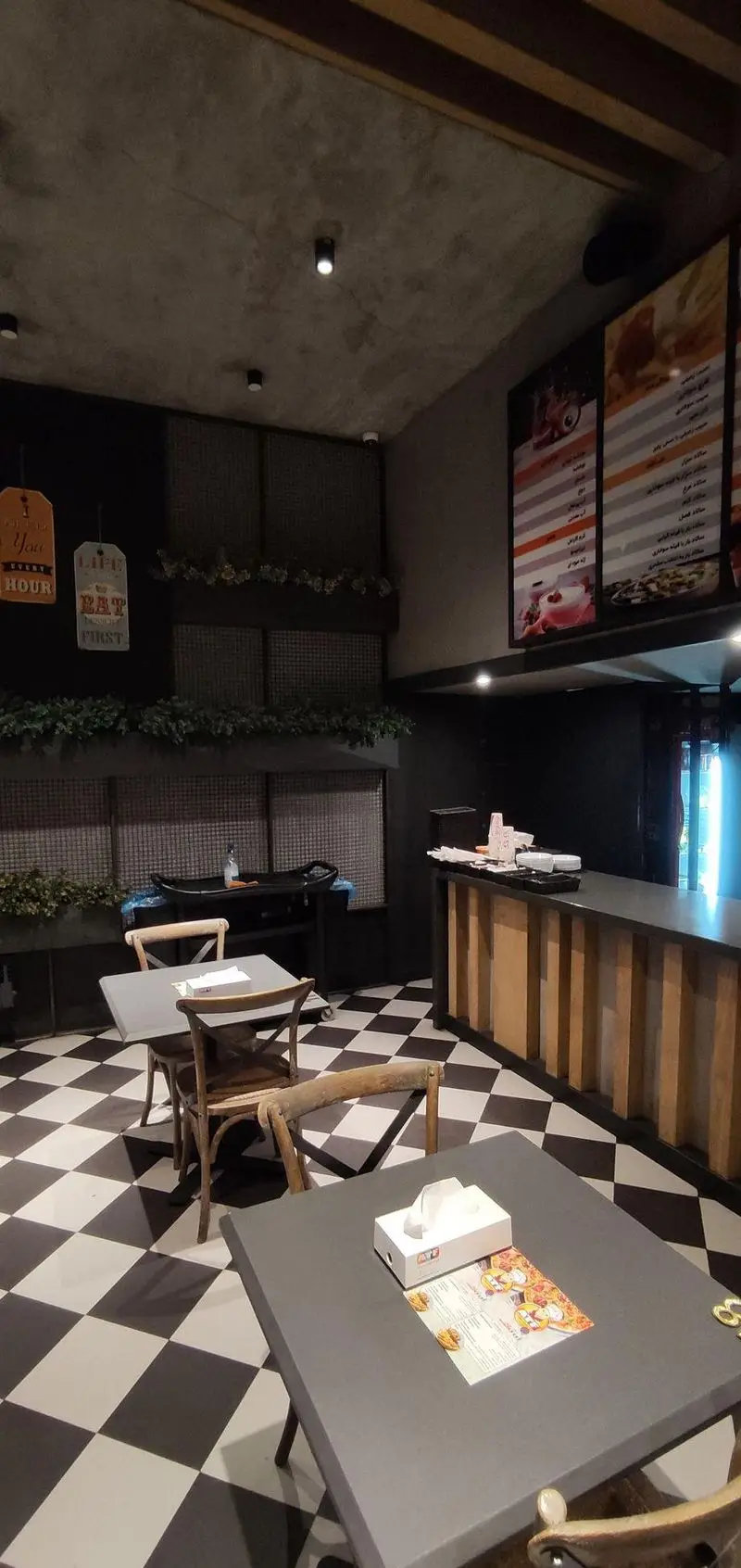 فضای داخلی شیک و مدرن رستوران ای تی اف شعبه کاشانی با کف شطرنجی، میز و صندلی چوبی و منوهای جذاب.