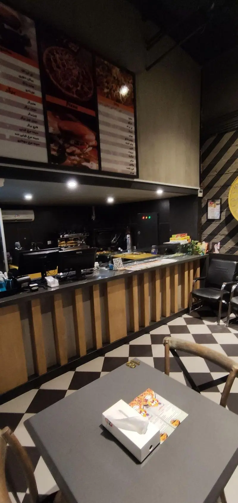 تصویری از فضای داخلی ای تی اف شعبه کاشانی، نمایشگر منوی جذاب پیتزا و همبرگر، پیشخوان مدرن و فضای غذاخوری دلنشین.