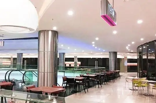 فضای داخلی وسیع و مدرن رستوران ایرانی فرندز اکسپرس، با میز و صندلی‌های چوبی و فلزی شیک، ستون‌های استیل براق و نورپردازی دلنشین برای تجربه‌ای لذت‌بخش از غذا.