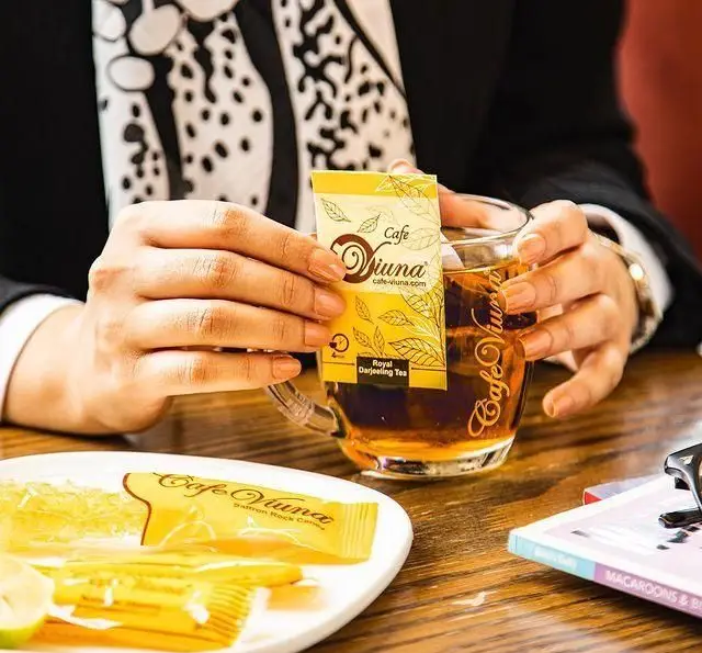 خانمی در حال لذت بردن از چای رویال دارجلینگ کافه ویونا در کنار نبات زعفرانی ویونا. تجربه ای دلنشین از نوشیدنی های کافه ویونا.