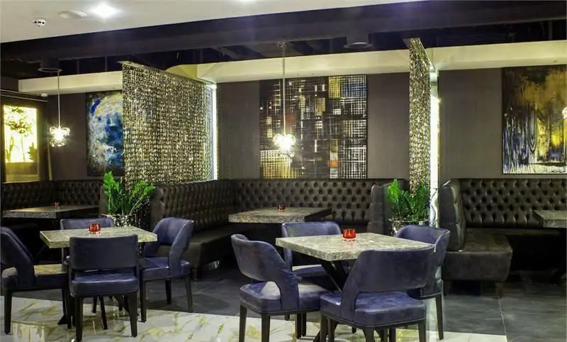 دکوراسیون داخلی شیک و مدرن کافه رستوران کالوک با مبلمان چرمی تیره، میزهای سنگی و صندلی‌های مخملی آبی. محیطی دنج و لوکس.