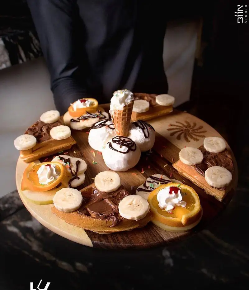 میز دسر متنوع کافه رستوران کالوک شامل وافل با نوتلا و موز، بستنی، و دسر پرتقالی. طعم‌های شیرین برای تجربه ای فراموش‌نشدنی.