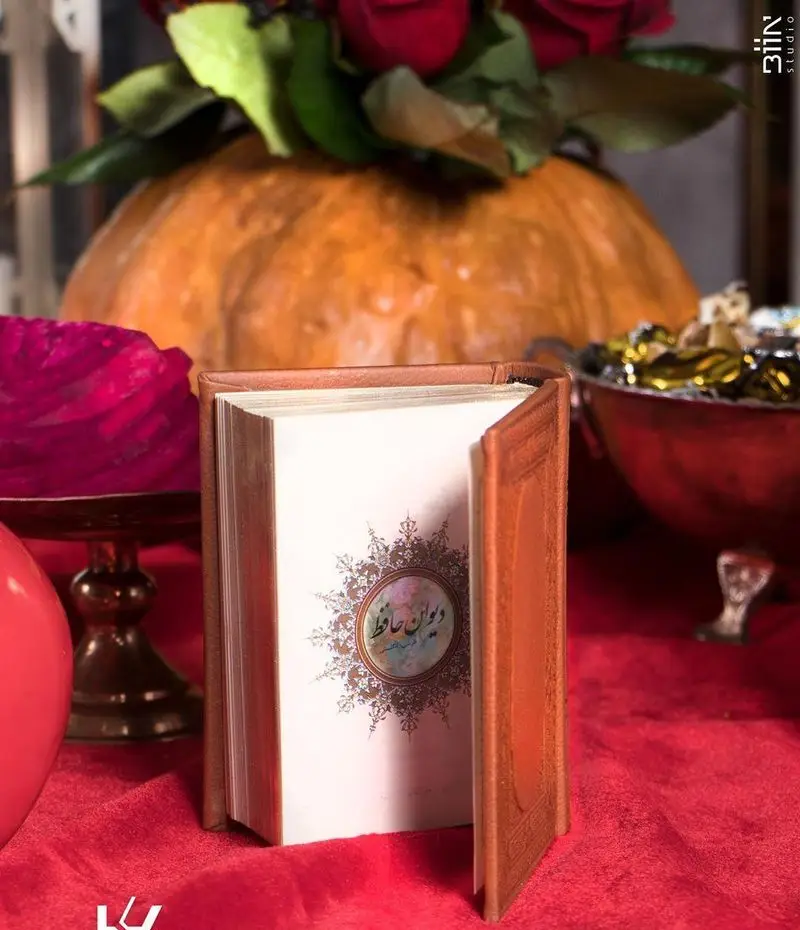 میز آرایی ویژه شب یلدا در کافه رستوران کالوک با دیوان حافظ، کدو حلوایی، گل‌های رز و خوراکی‌های سنتی.