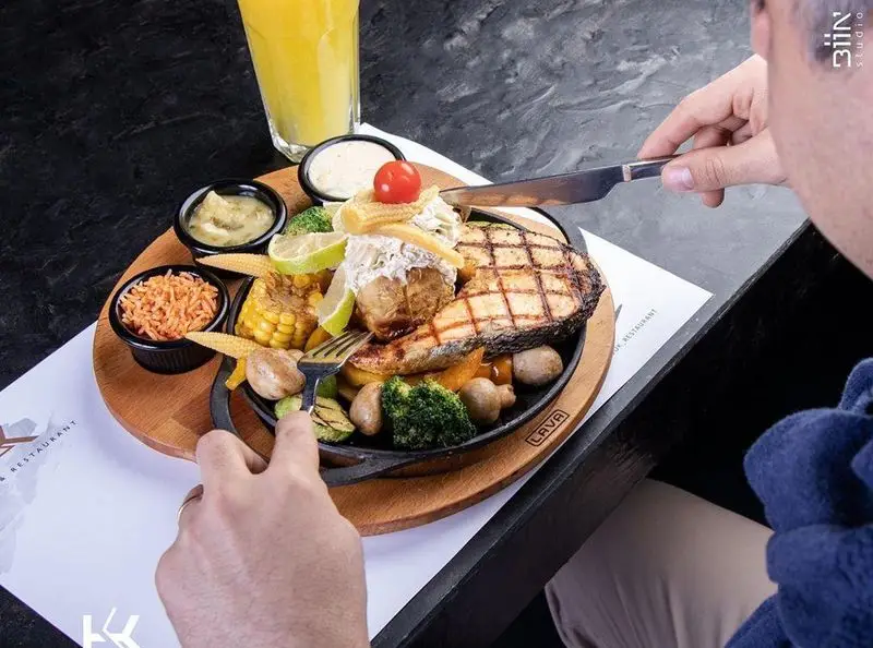 سرو ماهی گریل و سبزیجات تازه همراه سیب زمینی تنوری در کافه رستوران کالوک، یک غذای سالم و لذیذ.