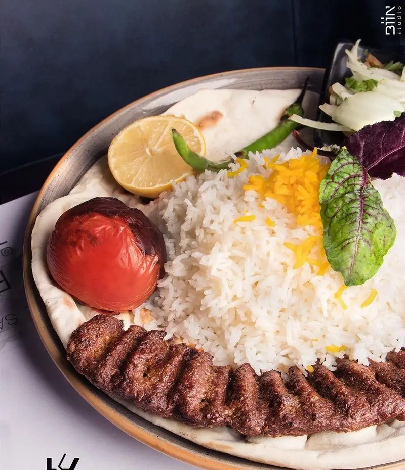 چلوکباب کوبیده لذیذ با برنج زعفرانی، گوجه کبابی و نان تازه در کافه رستوران کالوک. تجربه‌ای اصیل از غذای ایرانی.