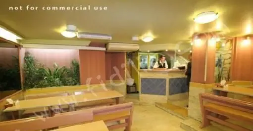 فضای داخلی دنج و دلنشین رستوران خانه کوچک با میز و نیمکت‌های چوبی، تزئینات گیاهی و پیشخوان پذیرش، آماده برای سرویس‌دهی.