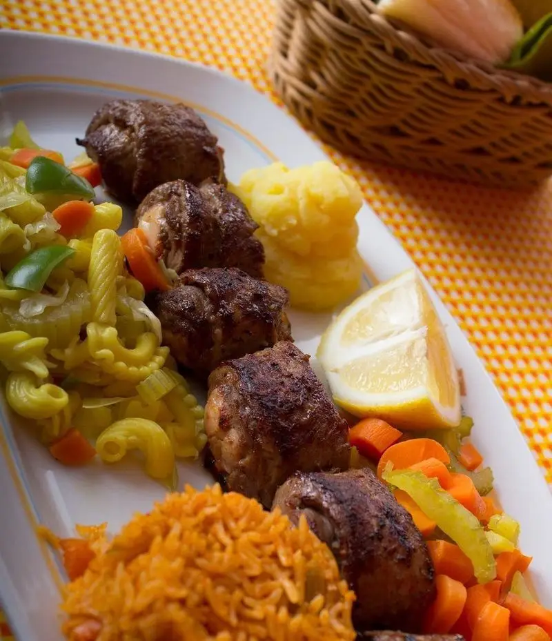 غذای لذیذ "خانه کوچک" شامل کباب لقمه، پاستای زرد با سبزیجات، پوره سیب زمینی، برنج نارنجی، سبزیجات متنوع و لیمو.
