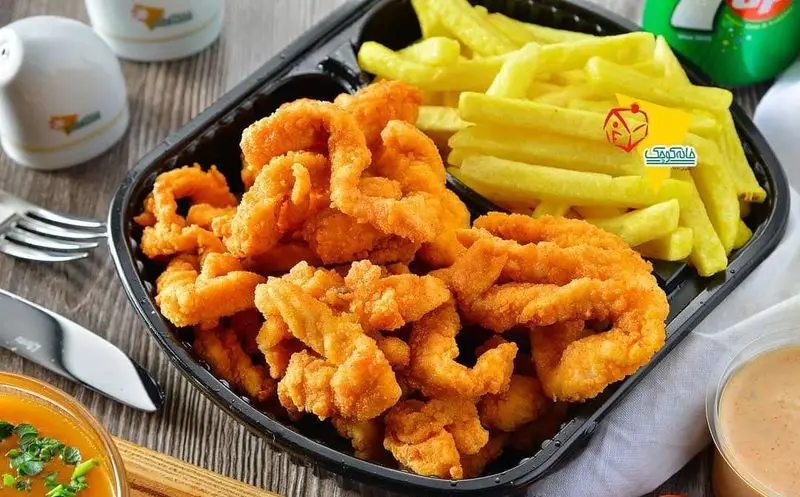 سفارش فست فود از خانه کوچک: میگو سوخاری ترد و سیب زمینی سرخ کرده طلایی، همراه سس دلپذیر و نوشابه. غذای آماده و لذیذ.