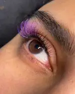 نمایی نزدیک از مژه‌های بلند و بنفش سالن زیبایی نیرا، چشم قهوه‌ای با اکستنشن مژه، آرایش چشم زنانه، زیبایی و جذابیت.