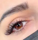 تصویر نزدیک از اکستنشن مژه والیوم مشکی و پرپشت به همراه لیفت و مرتب‌سازی ابروهای طبیعی در سالن زیبایی و آرایشگاه زنانه