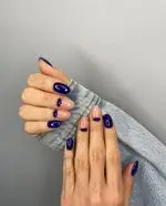 جدیدترین مدل طراحی ناخن با لاک سرمه‌ای تیره و بیس نود به صورت هلال ماه روی ناخن‌های بادامی شیک و دخترانه در سالن زیبایی