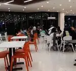نمای داخلی رستوران شالِت، فضایی مدرن و دنج با مشتریانی که شب‌هنگام دور میزهای سفید و صندلی‌های نارنجی و سفید جمع شده‌اند. موسیقی زنده در حال اجراست.