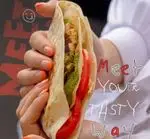 عکس رپ مرغ گریل میت وی با تکه‌های مرغ، سس سبز و گوجه تازه. غذای سالم و خوشمزه از Meet Way برای راه حل سریع و لذیذ.