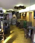 فضای داخلی گرم و دلنشین کافی شاپ 4 چوب با دکوراسیون چوبی، تنور پیتزا آجرپز، پیانو و میز و صندلی‌های مدرن چوبی.
