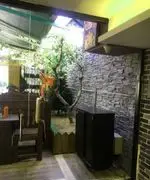 نمایی زیبا از فضای داخلی و دکوراسیون چوبی کافی شاپ 4 چوب با فضای سبز، درختان طبیعی، دیوار سنگی و میز و صندلی‌های چوبی دنج.