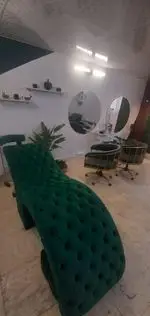 طراحی دکوراسیون داخلی سالن زیبایی با تخت مژه و ماساژ مخمل سبز یشمی، آینه‌های گرد دیواری و صندلی‌های مدرن آرایشگاهی