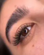 نمایی نزدیک از چشم با اکستنشن مژه والیوم بی‌نظیر و طراحی ابروی طبیعی، خدماتی ممتاز در سالن زیبایی هیلان.