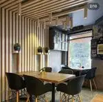 نمایی از دکوراسیون داخلی مدرن و دنج کافه کلاور با دیوارها و سقف چوبی، میز و صندلی‌های شیک و نورپردازی جذاب.