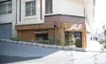 کافه کلاور: تصویری از نمای بیرونی کافه با طراحی چوبی عمودی جذاب، تابلوی نام کافه به رنگ سفید، ورودی شیشه‌ای و فضای سبز مقابل آن در خیابان تهران.