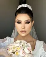مدل میکاپ و شینیون عروس ۲۰۲۴ سالن زیبایی آزیتا امیری با آرایش چشم اسموکی، مژه‌های بلند، رژ لب نود و تاج درخشان، ویژه بانوان.