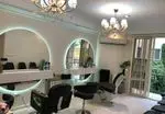 طراحی دکوراسیون داخلی آرایشگاه زنانه با آینه‌های بزرگ دایره‌ای بک‌لایت، صندلی‌های اصلاح مدرن و لوسترهای شیک کریستالی