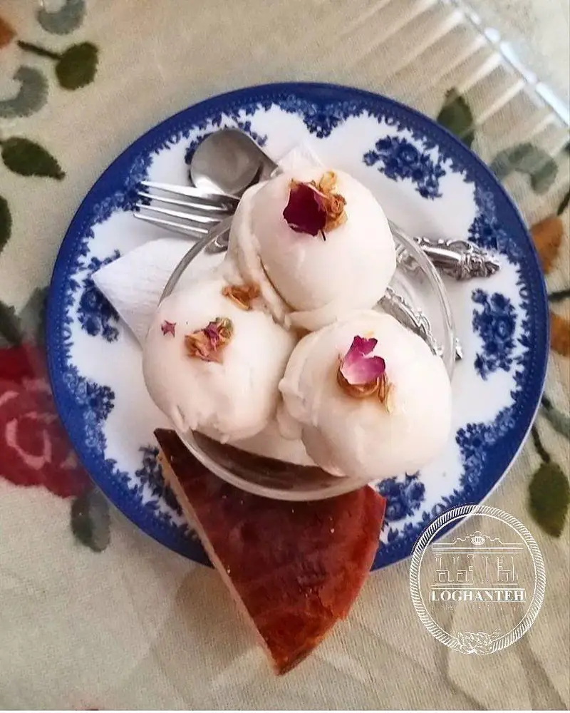 بستنی سفید سنتی کافه لقانطه با گلبرگ رز و تکه کیک، روی بشقاب طرح‌دار. لذت دسر در فضای آرام کافه تهران.