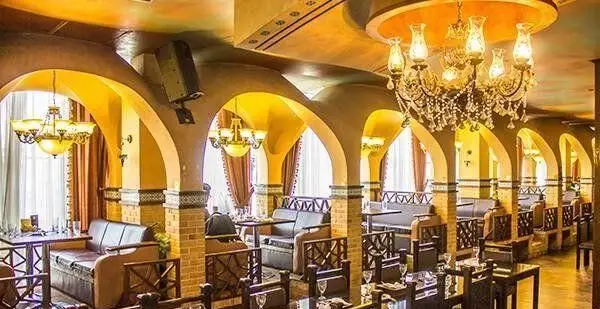 رستوران ایرانی شهربانو با دکوراسیون سنتی و فضای دلنشین، میزها و صندلی‌های چوبی، آلاچیق‌ها و لوسترهای زیبا برای یک تجربه غذایی اصیل.