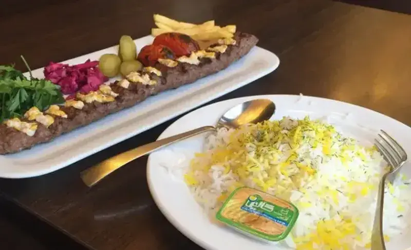 چلو کباب کوبیده لذیذ رستوران ایرانی شهربانو با برنج زعفرانی، گوجه کبابی، سیب زمینی و مخلفات تازه. غذای اصیل ایرانی.