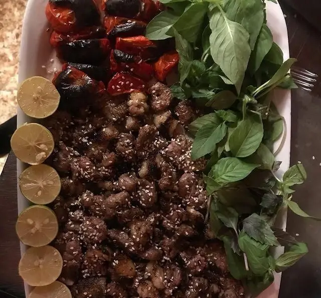 بشقاب کباب جگر ذغالی پامچال با دانه کنجد، گوجه کبابی، لیمو و سبزی تازه. یک غذای سنتی و خوشمزه ایرانی.