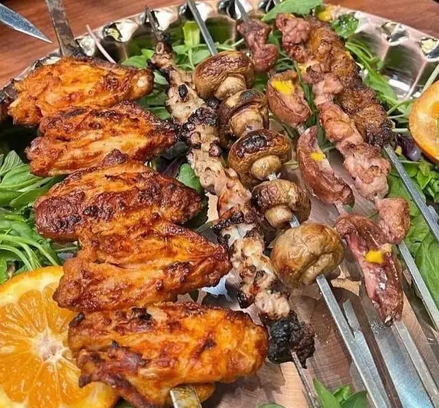 تصویری از سینی کباب ذغالی جگر ذغالی پامچال شامل: جوجه کباب بال، کباب قارچ و کباب گوشت تازه، همراه با سبزیجات.