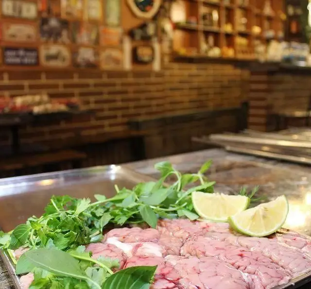 سینی آماده‌سازی مغز تازه گوسفندی، سبزیجات معطر و برش‌های لیمو برای کباب، در محیط گرم و سنتی جگر ذغالی پامچال تهران.