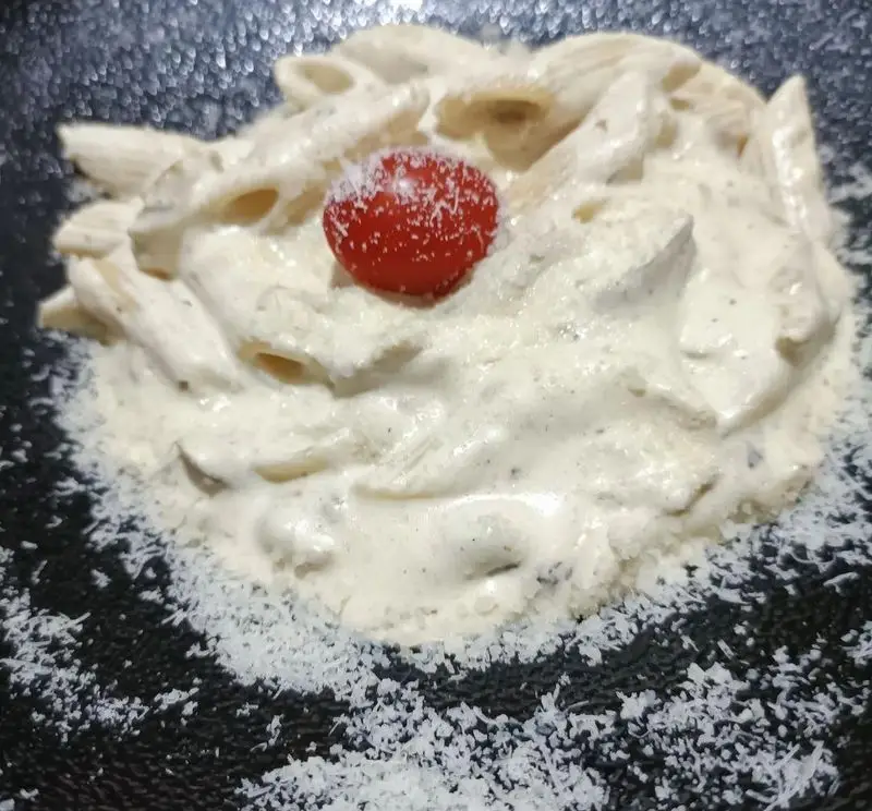 پاستا سس سفید پنه خامه‌ای و خوش‌عطر، با گوجه فرنگی گیلاسی و پودر پنیر تزئین شده، انتخابی دلپذیر از فست فود کاوان.