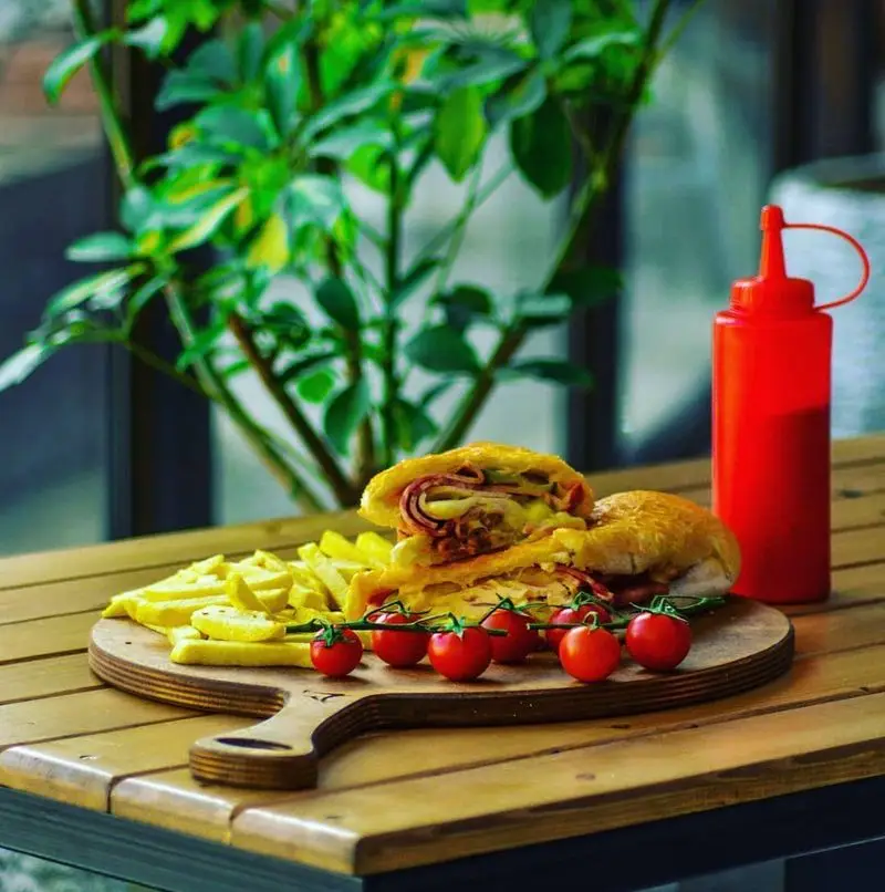 ساندویچ و سیب زمینی سرخ کرده خوشمزه فست فود کاوان با گوجه گیلاسی و کچاپ. ایده‌آل برای یک وعده غذایی سریع و لذیذ در کاوان.