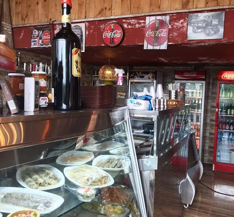 نمای داخلی کافه رستوران لوکا، ویترین پر از غذاهای ایرانی و محلی تازه، دکوراسیون چوبی، بطری نوشیدنی بزرگ و یخچال‌های کوکاکولا.