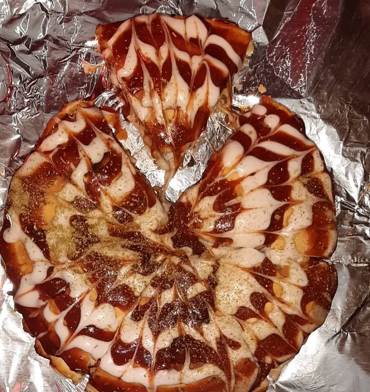 دسر پیتزایی خاص ساندویچ سن سون با تزئین سس شکلاتی و سفید طرح‌دار، ایده‌آل برای یک تجربه شیرین و متفاوت.