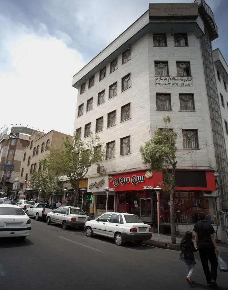 تصویری از نمای بیرونی فست فود و ساندویچی سن سون در خیابانی پر رفت و آمد در تهران، با مردم و ماشین ها در اطراف.