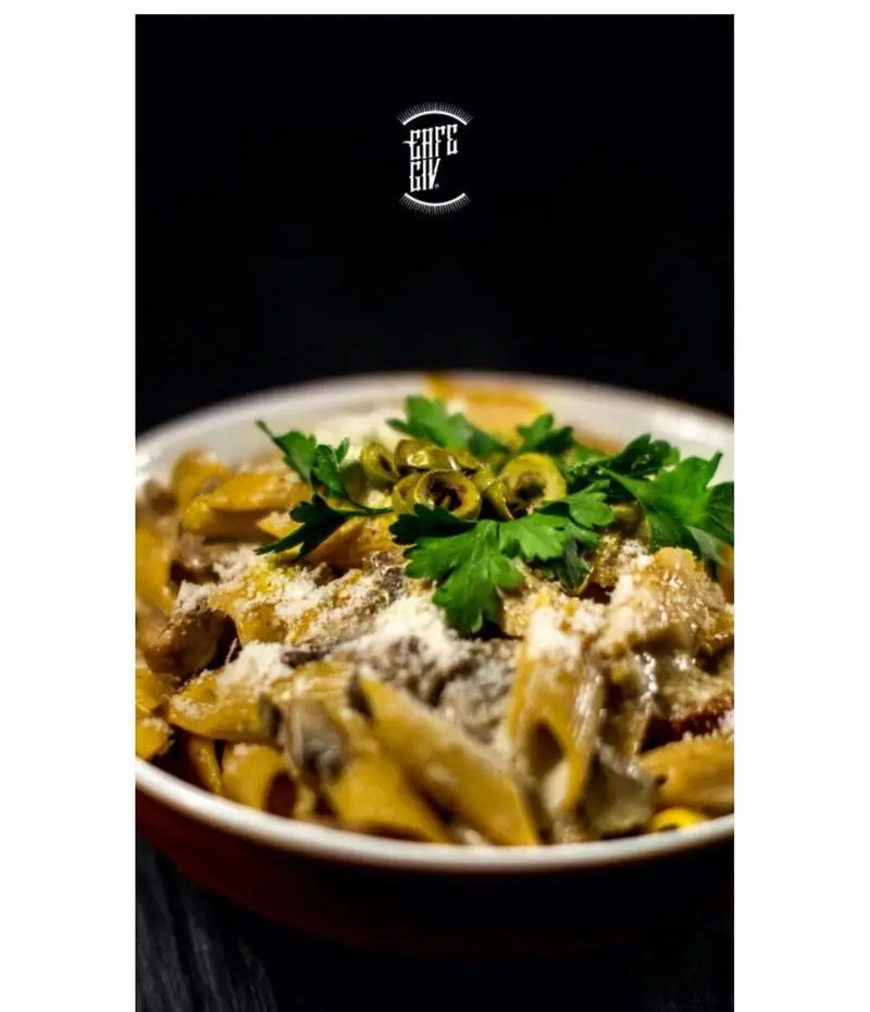 کاسه‌ای از پاستا پنه با سس قارچ و مرغ، تزئین شده با پنیر پارمزان، زیتون و جعفری، غذای خوشمزه کافه گیو