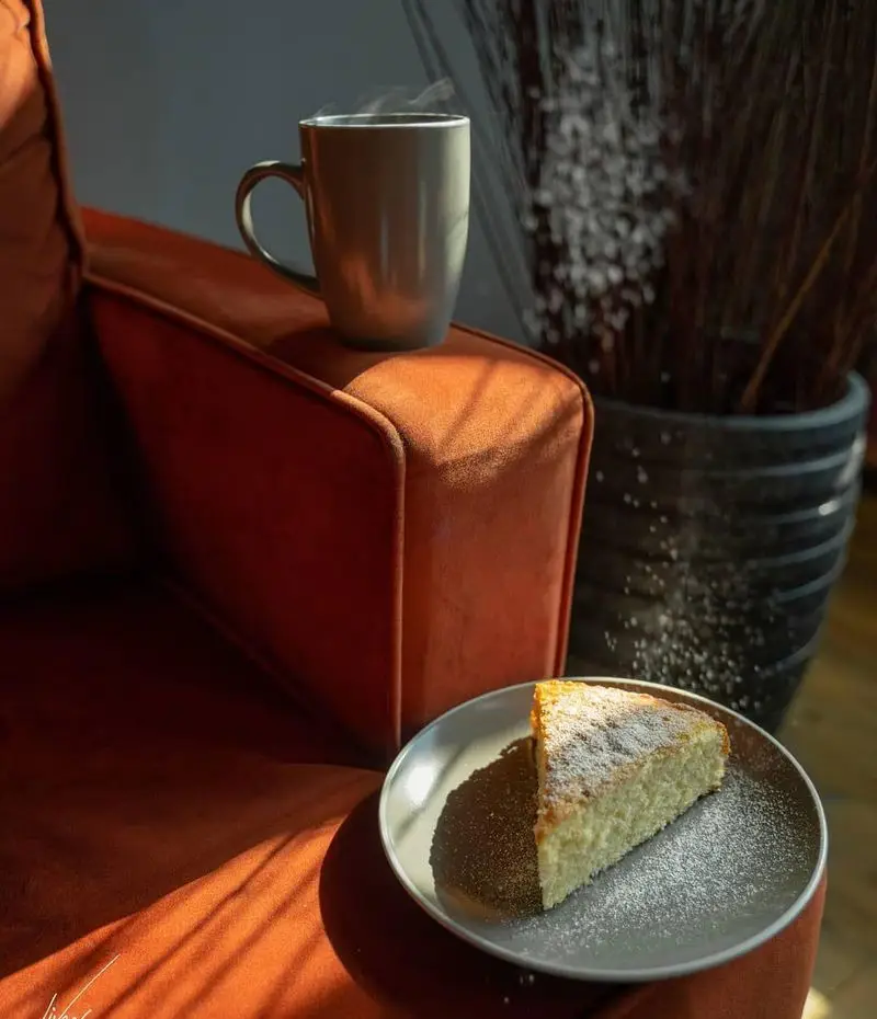 لذت یک فنجان نوشیدنی گرم و برش کیک شیرین در فضایی دنج و آفتابی کافه لیو. ایده‌آل برای استراحتی دلنشین.