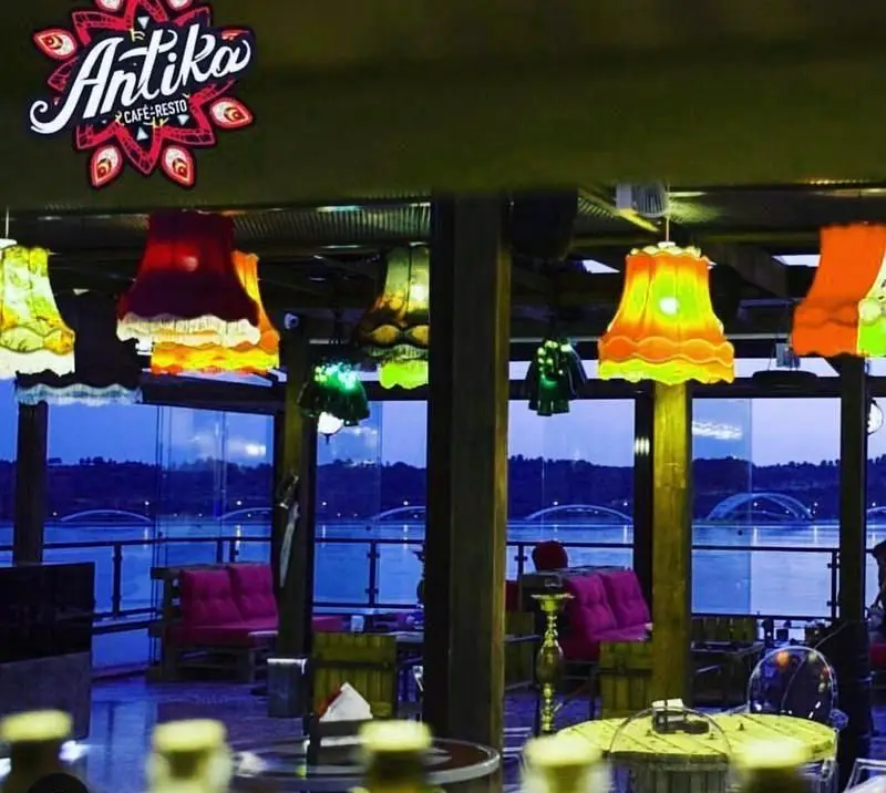 فضای داخلی کافه رستوران آنتیکا با لوسترهای فانتزی و رنگی، دکوراسیون گرم و منظره شبانه کنار آب، تجربه‌ای خاص ارائه می‌دهد.