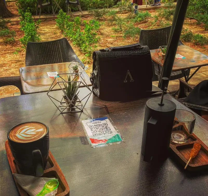 میز کافه آبمیوه و بستنی بهدونه در فضای باز، با قهوه لاته آرت، منوی QR، دکور زیبا و آرامش‌بخش، مناسب برای دورهمی.