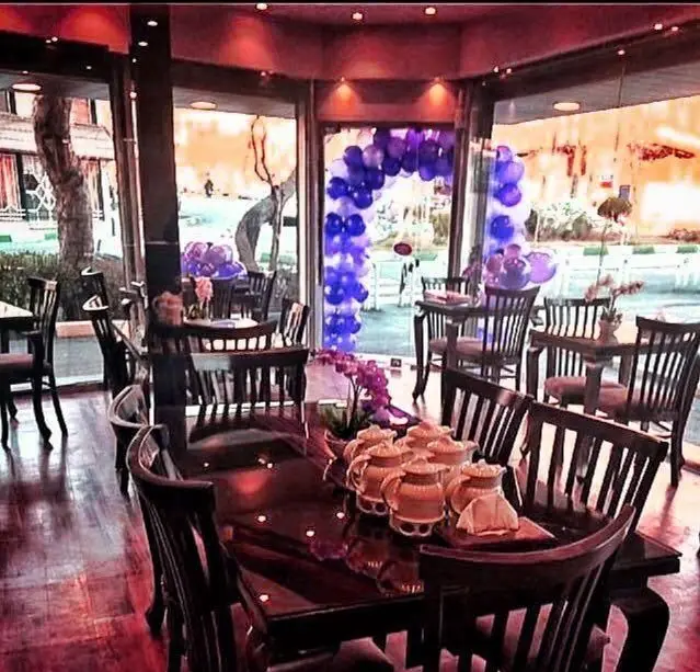 فضای داخلی دنج و شیک رستوران ایرانی دیگی تنوری با میزهای چوبی، صندلی‌های راحت و تزئینات جشن، مناسب برای دورهمی و تجربه غذا.