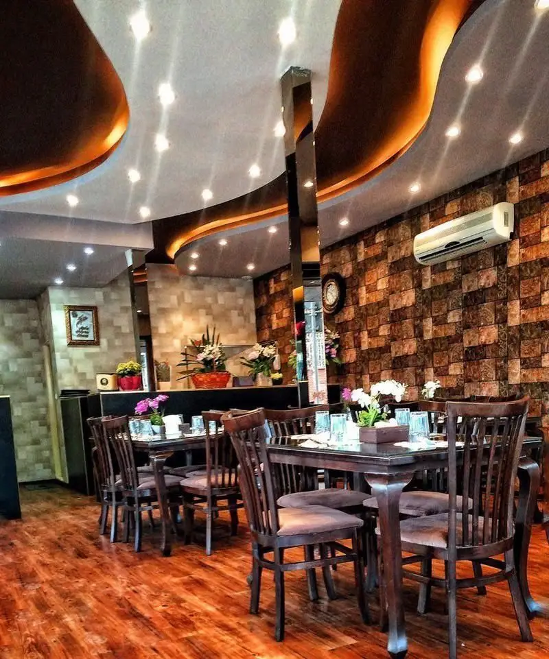 دکوراسیون داخلی رستوران دیگی تنوری، رستوران ایرانی در فضایی دلنشین با میز و صندلی‌های چوبی، سقف نورپردازی و دیوارهای آجری.