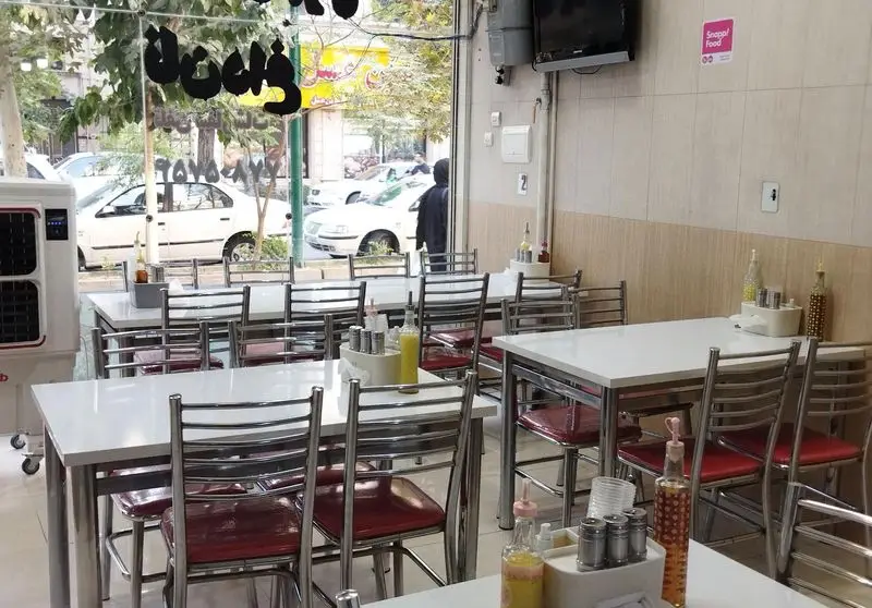 تصویری از محیط داخلی طباخی شبهای تهران با چیدمان ساده و تمیز میز و صندلی‌ها، ایده‌آل برای صرف کله‌پاچه.