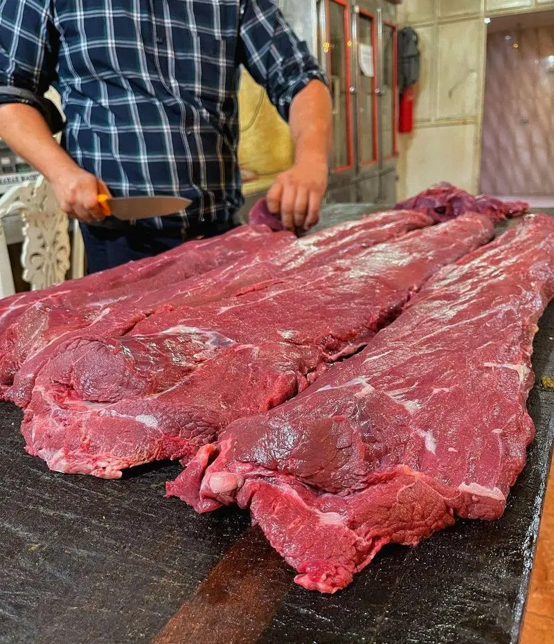 قصاب ماهر در حال آماده‌سازی و برش دقیق گوشت تازه برای طبخ انواع غذاهای لذیذ در رستوران وی آی پی کاظمی.